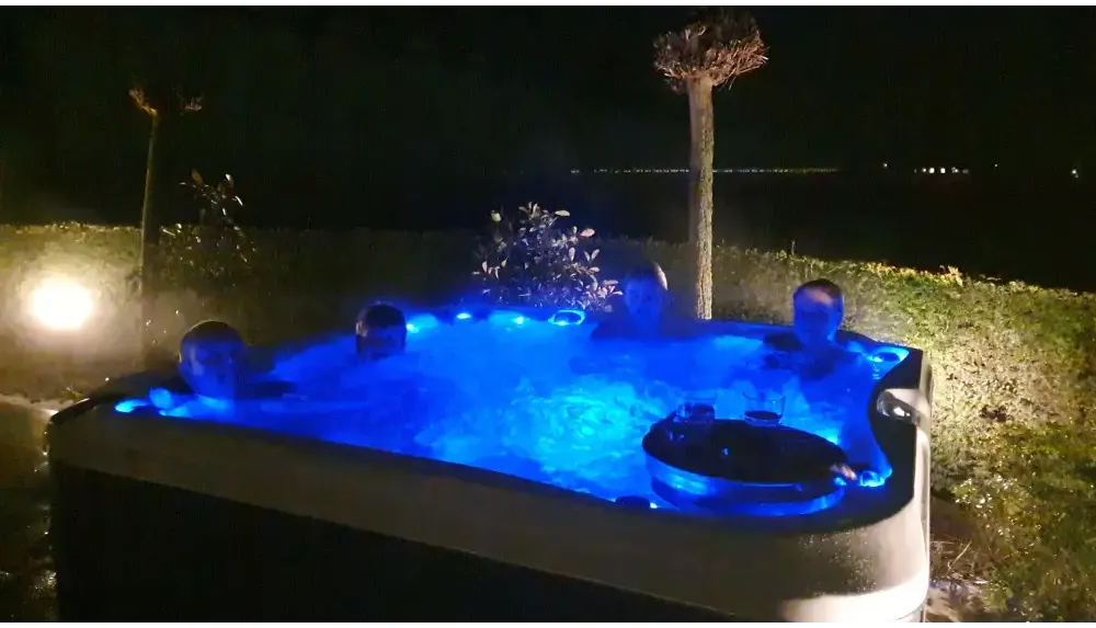 PassionSpa Delight -poreallas – sininen valaistus, rentoutuvia ihmisiä, yöllä PassionSpa Delight -poreallas – sininen valaistus, rentoutuvia ihmisiä, yöllä